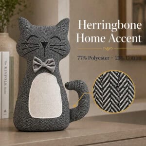 Charcoal cat door stopper on a wood surface beside books, with a magnified circle showing the herringbone weave. On-image text: "Herringbone Home Accent," "77% Polyester · 23% Cotton."