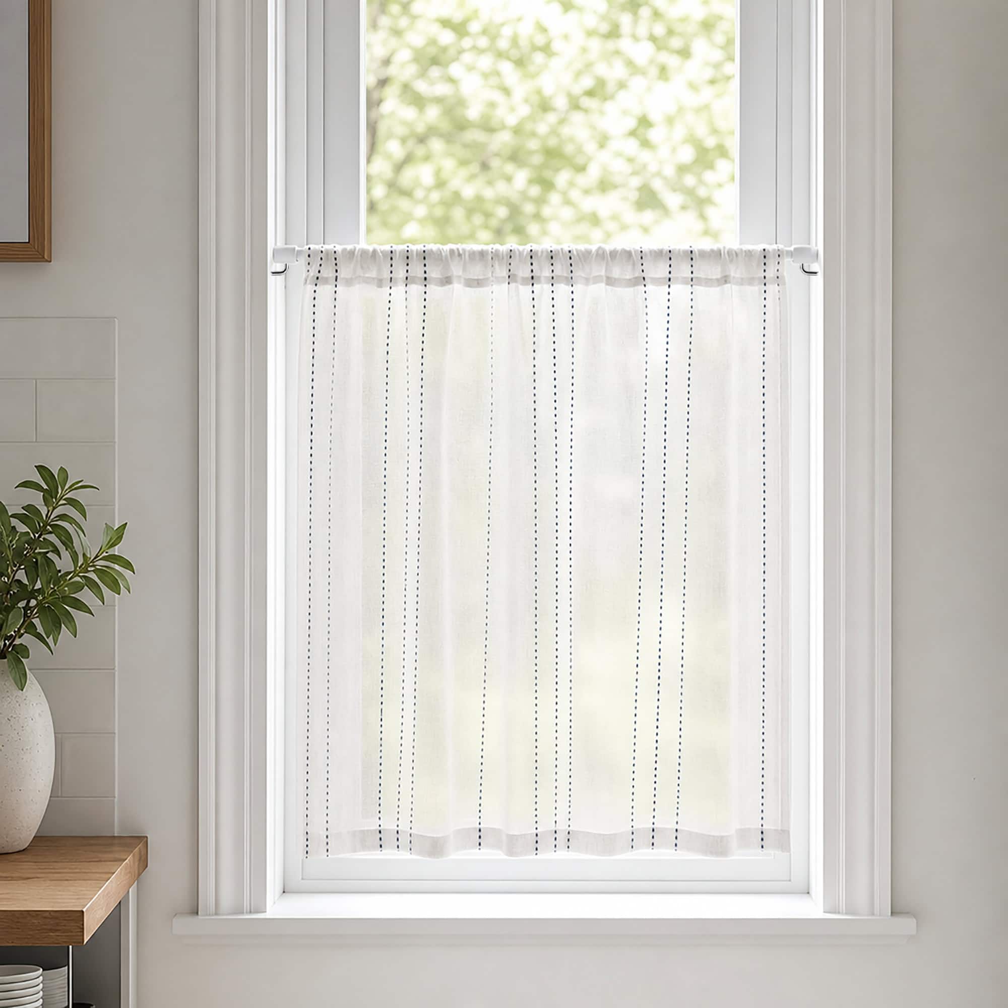 White cafe rod holding a sheer striped tier curtain across a bright kitchen window, styled with a green plant and light neutral decor for a farmhouse look.