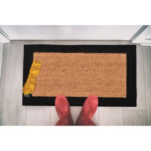 Black-border coir doormat 24x13 seen from above with boots and umbrella