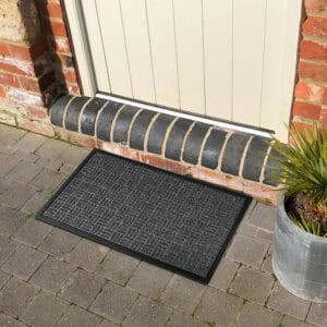 Gray checkerboard doormat outside a front door on stone pavers