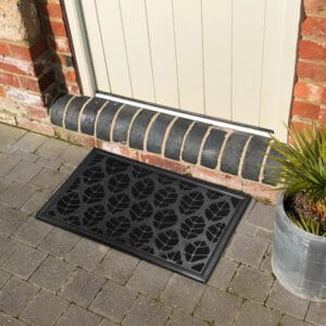 Black leaf design doormat placed in front of an exterior door