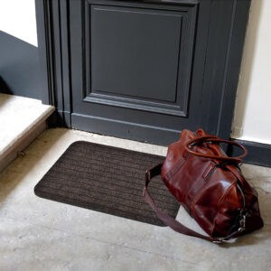 Brown entry mat placed at an indoor doorway with bag