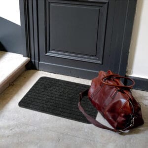 Anthracite gray entry mat placed at an indoor doorway with bag
