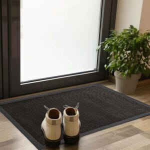 Black entrance door mat placed indoors near glass door