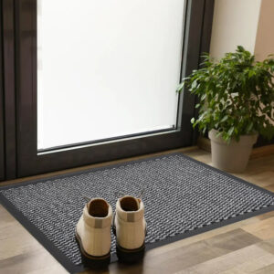 Gray entry door mat with rubber border placed indoors with shoes