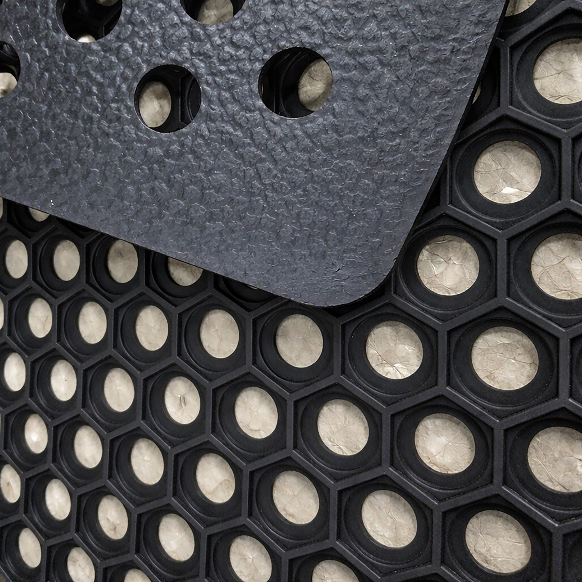 Close-up of thick rubber mat showing open hole pattern and textured surface