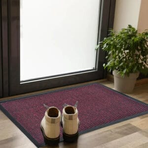 Red burgundy entry door mat with rubber border placed indoors with shoes