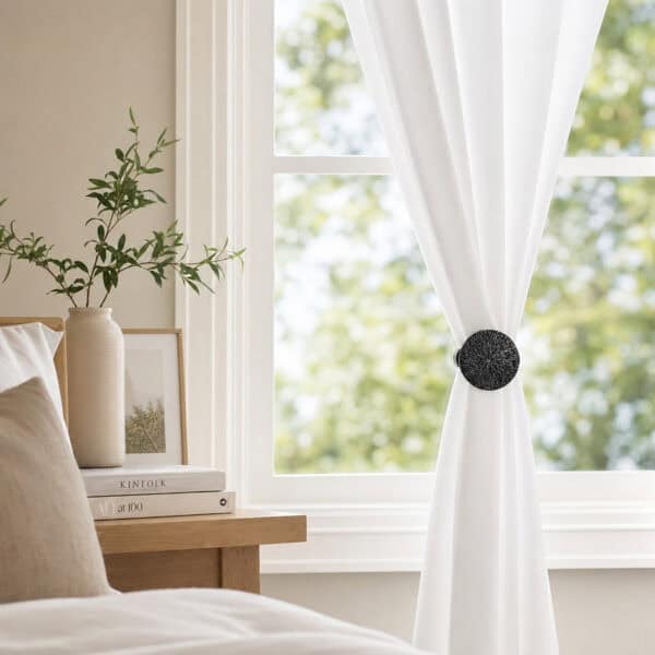 Black round curtain tieback clip holding back white drapes in a room