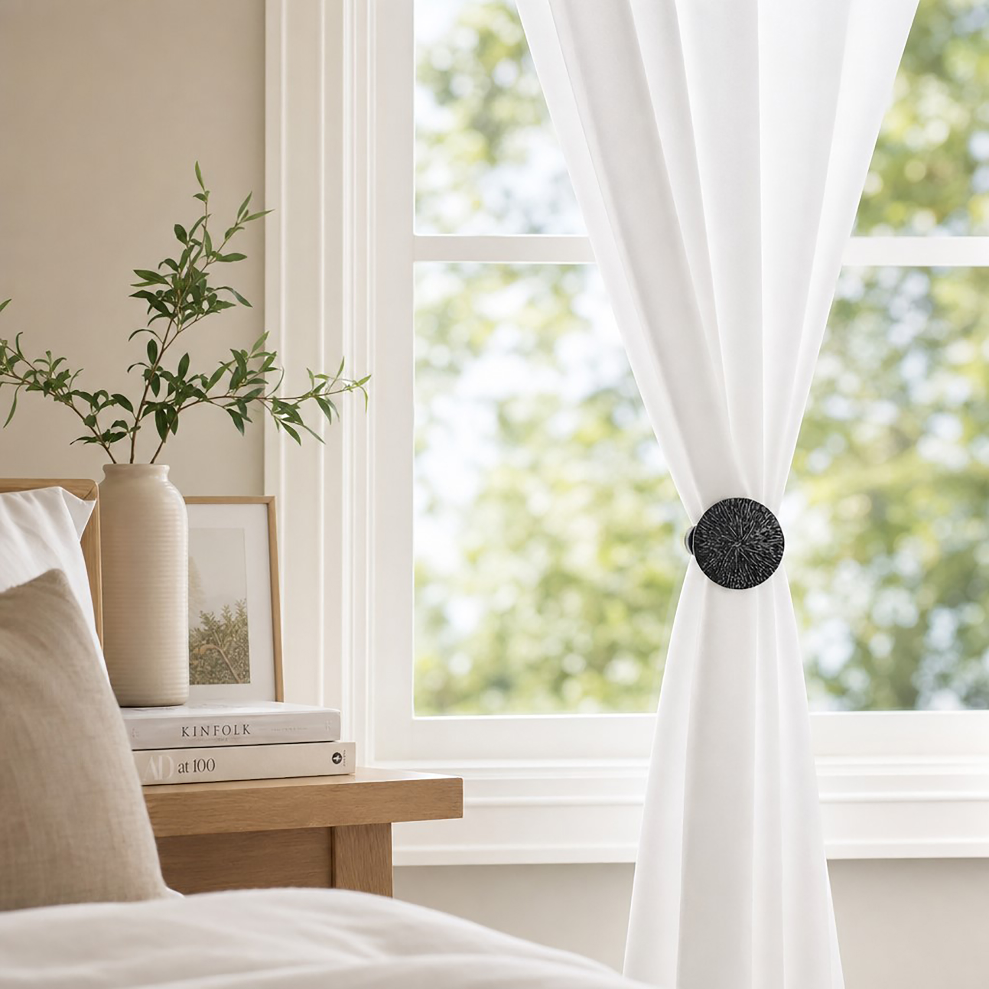 Black round curtain tieback clip holding back white drapes in a room