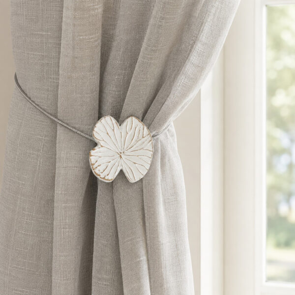 Lifestyle grège: White water lily magnetic tieback holding a light gray sheer linen curtain by a sunlit window