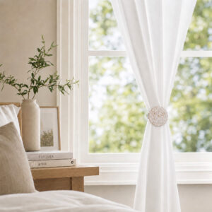 White and gold round curtain tieback clip holding back white drapes in a room