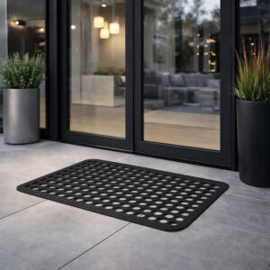 Outdoor rubber door mat placed in front of a modern glass entry door