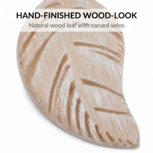 Close-up of natural wood leaf tieback showing warm grain and carved veins