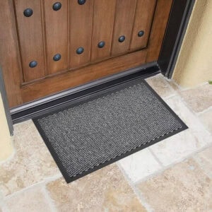Gray indoor outdoor doormat placed by front door on stone floor