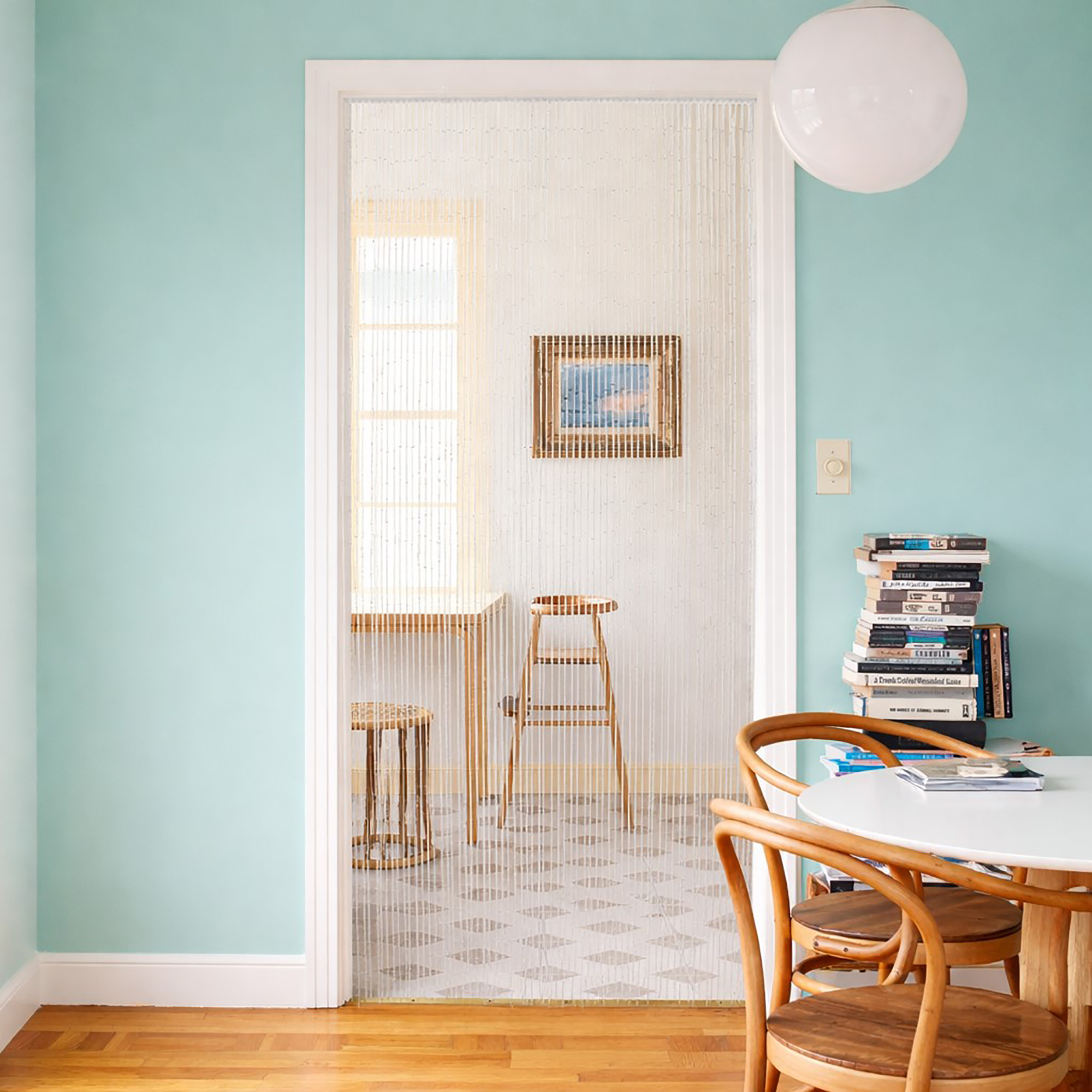 Bamboo beaded door curtain separating dining space with turquoise walls