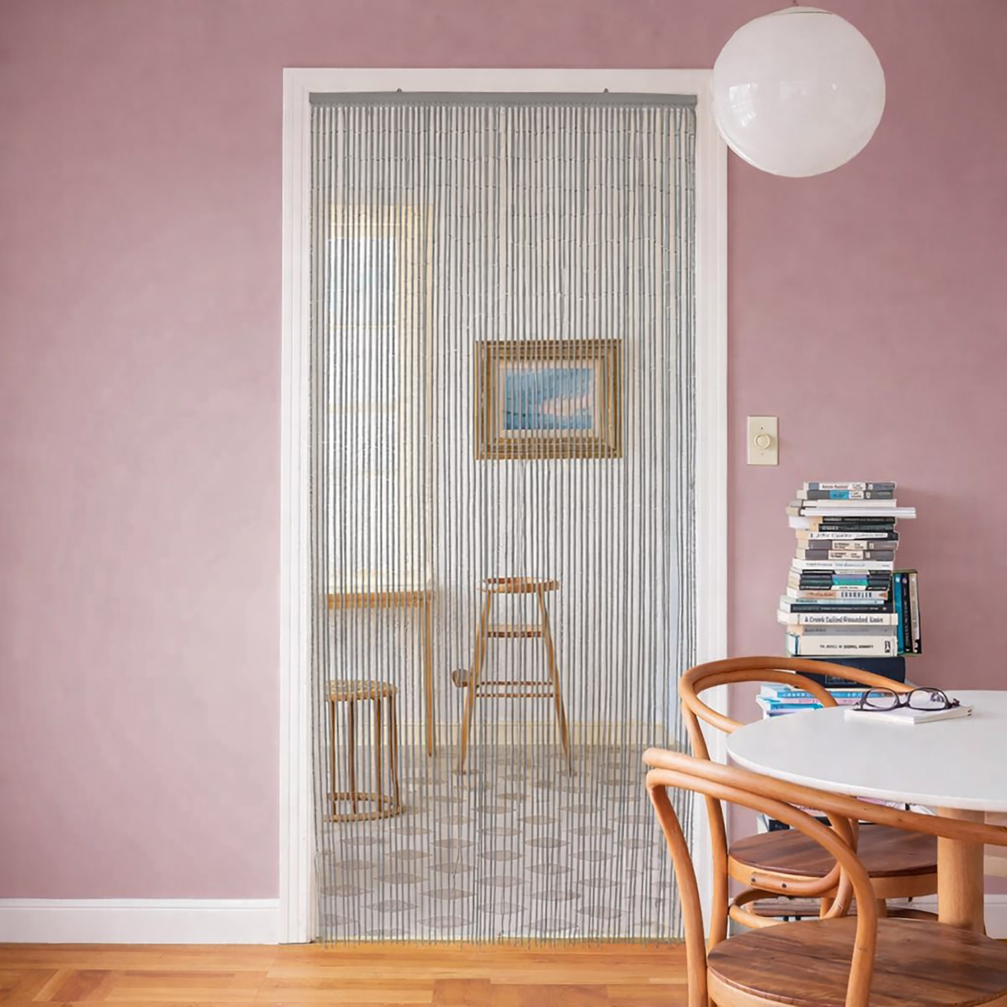Bamboo beaded door curtain in doorway with pink wall interior