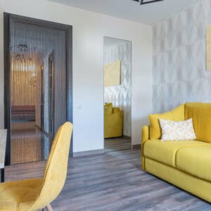 Gray bamboo beaded door curtain in modern living room with yellow sofa
