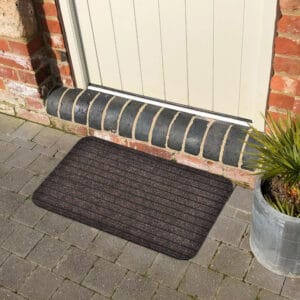 Brown outdoor doormat in front of an exterior door on stone pavers