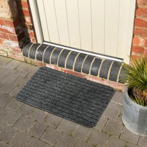 Gray outdoor doormat in front of an exterior door on stone pavers