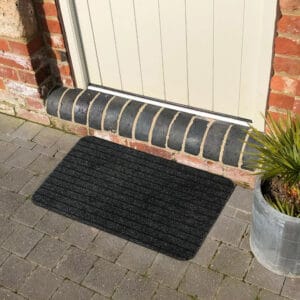 Anthracite gray outdoor doormat in front of an exterior door on stone pavers