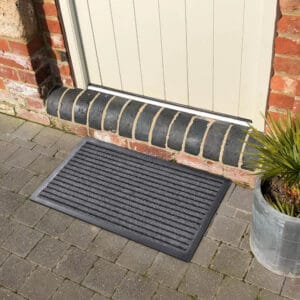 Outdoor striped front door mat on stone patio in front of exterior door