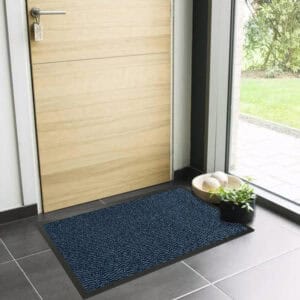 Blue indoor entryway mat with low profile design near wooden door