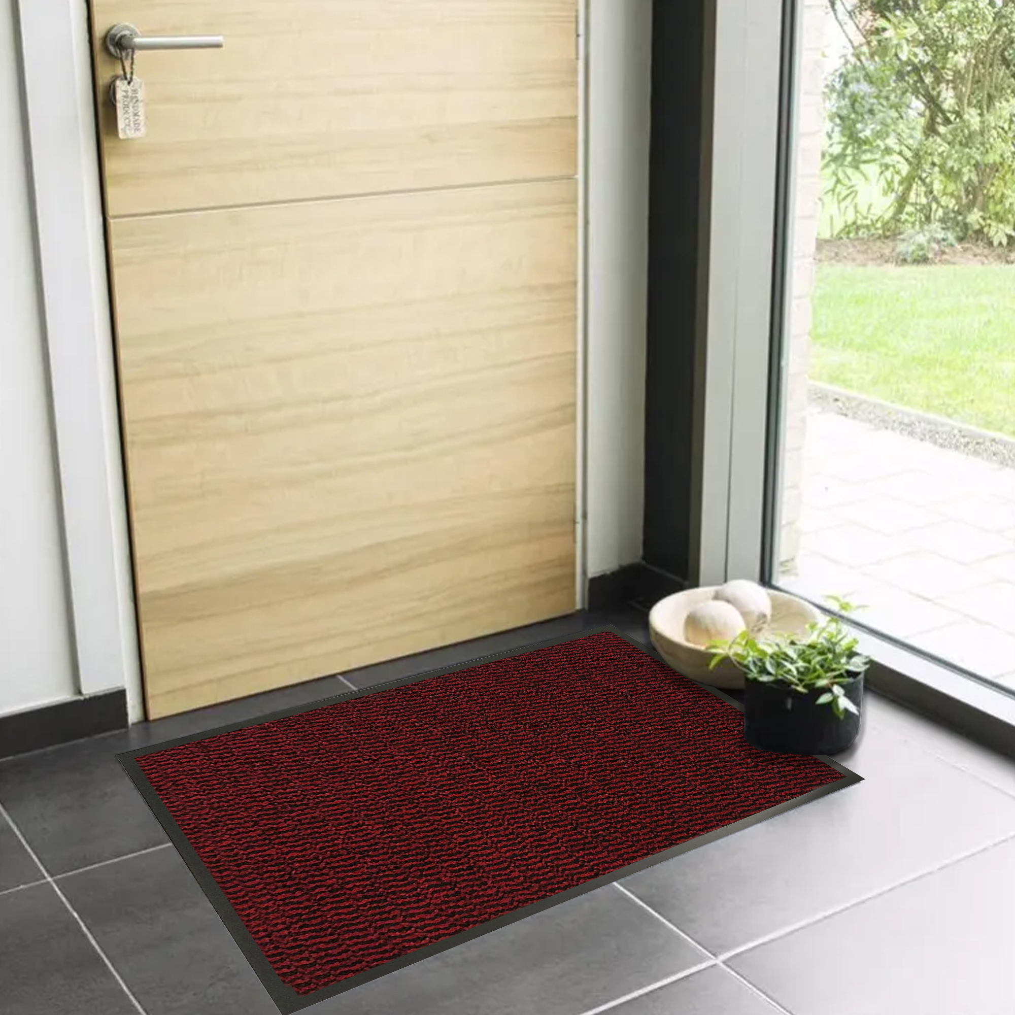 Red indoor entryway mat with low profile design near wooden door