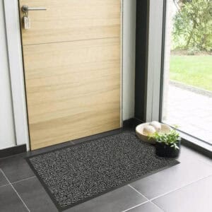 Gray indoor entryway mat with low profile design near wooden door