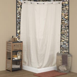 "Acacia wood bathroom storage unit with open shelves styled beside a cream shower curtain and pebble wall"