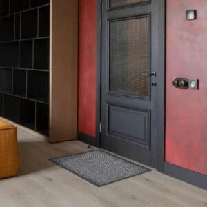 Gray indoor outdoor doormat placed by front door on wood floor