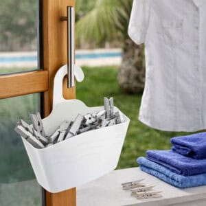 White hanging shower caddy filled with clothespins hanging on outdoor door handle