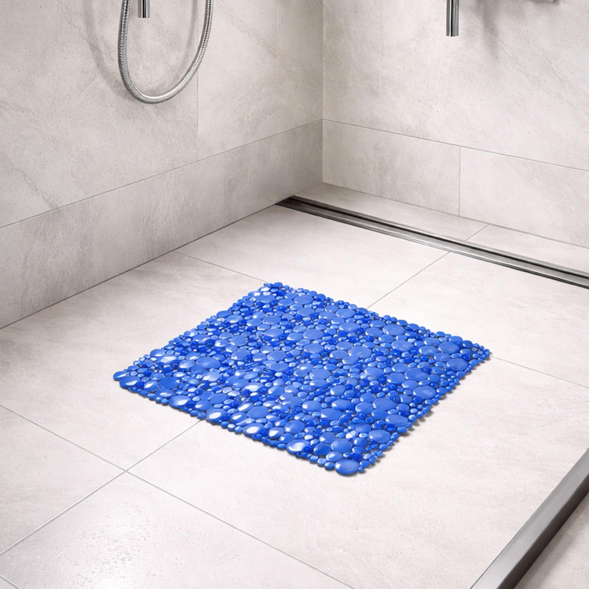 Navy blue bubble-pattern shower mat on beige tile shower floor with chrome handheld showerhead