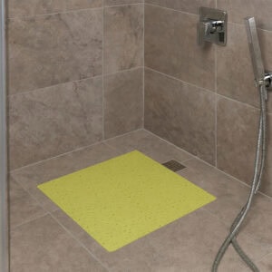 Lime green bubble-pattern shower mat on brown tile shower floor with chrome fixtures