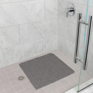Taupe bubble-pattern shower mat on light gray tile shower floor with chrome fixtures and glass door