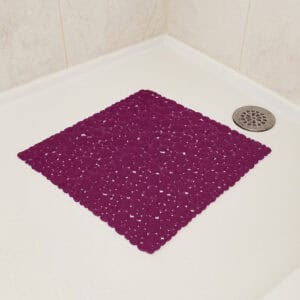 Purple bubble-pattern shower mat on white shower base with beige tile walls