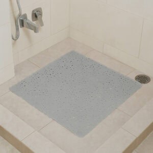 Pearly gray bubble-pattern shower mat on beige tile shower floor with chrome fixtures