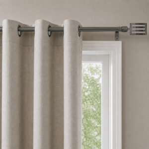 Beige grommet curtains hanging from the graphite adjustable curtain rod beside a window