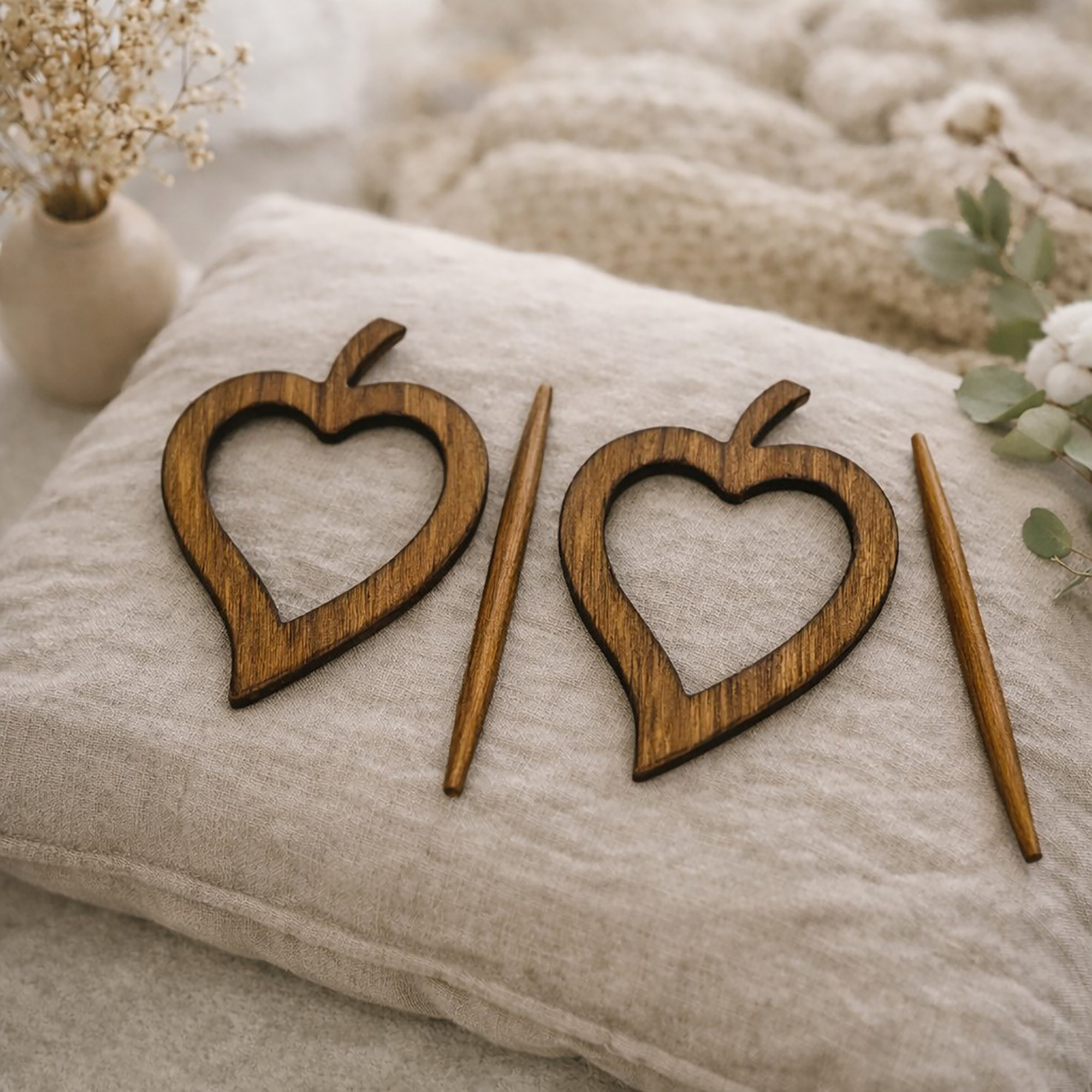"Set of two dark natural wood heart frames and pins displayed on linen cushion"