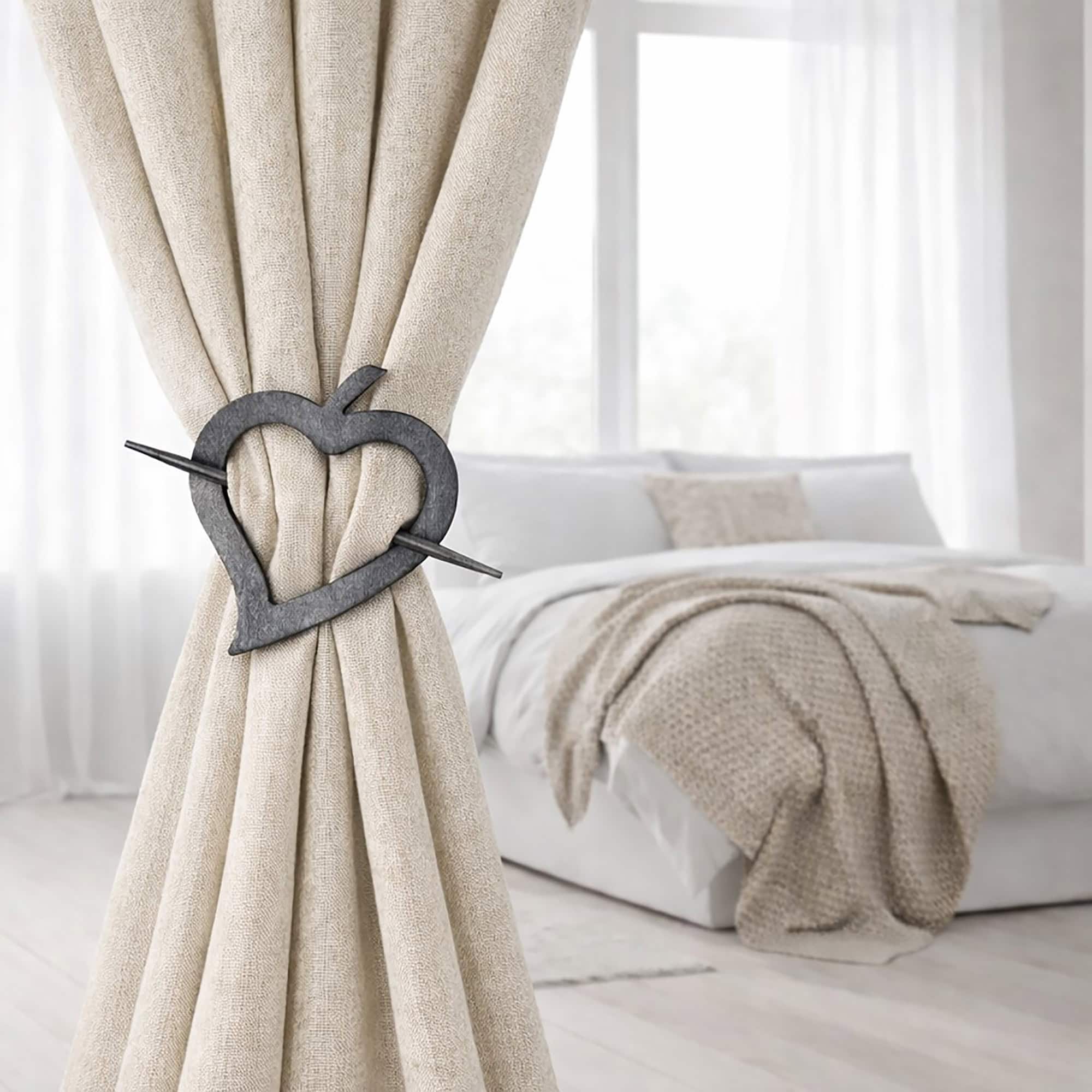 "Gray wood heart tieback on linen drape in minimalist bedroom"