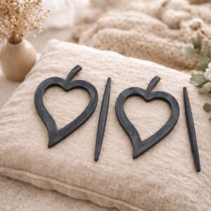 "Set of two dark washed wood heart frames and pins displayed on linen cushion"