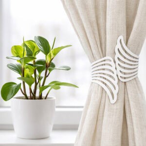 "White angel wings tieback on cream curtain beside a potted plant on a windowsill"