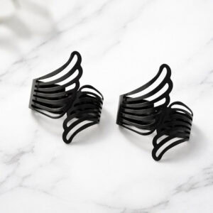 "Two black metal angel wings curtain tiebacks displayed on a marble surface"