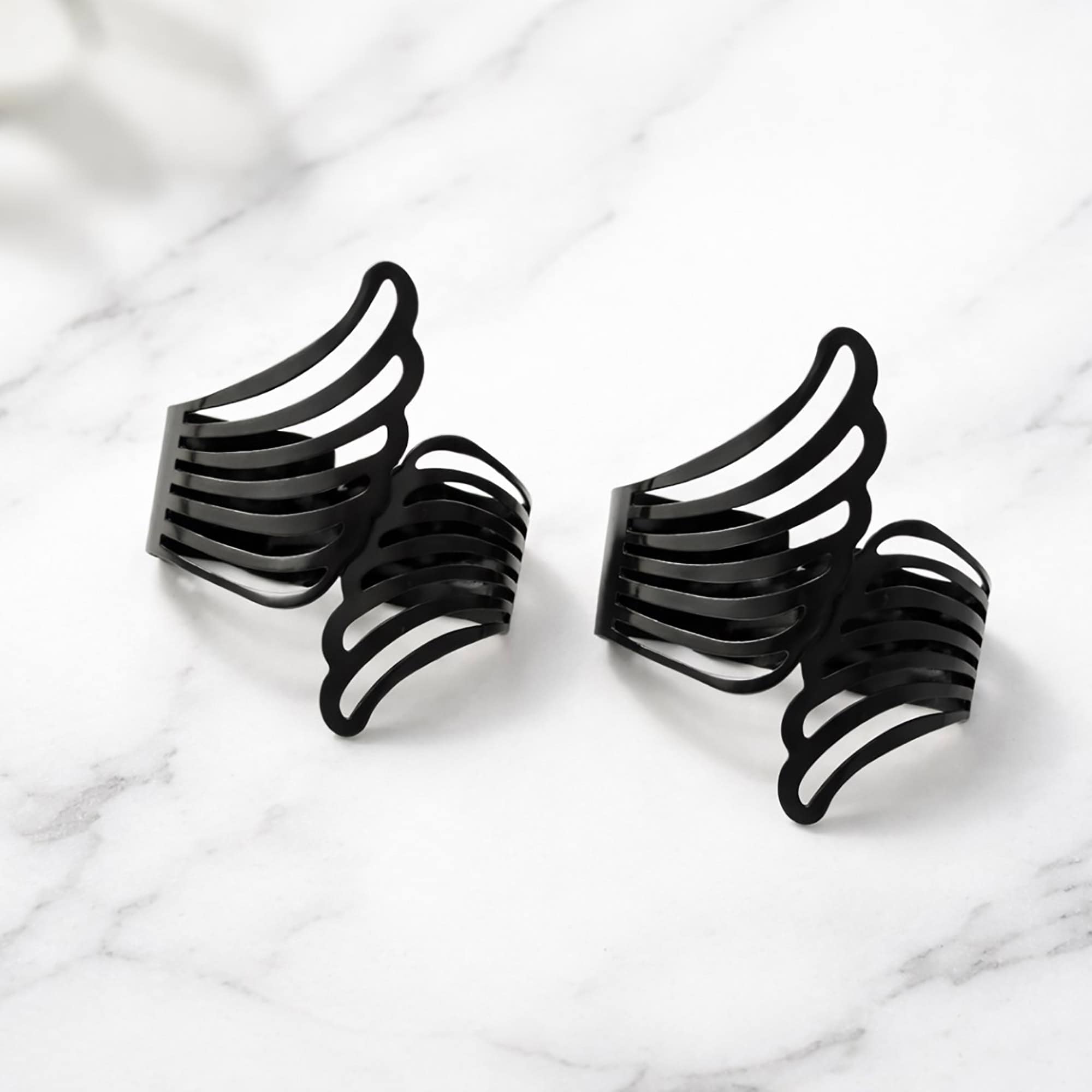 "Two black metal angel wings curtain tiebacks displayed on a marble surface"
