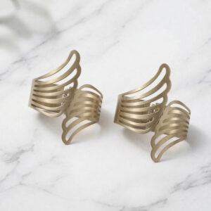 "Two gold metal angel wings curtain tiebacks displayed on a marble surface"