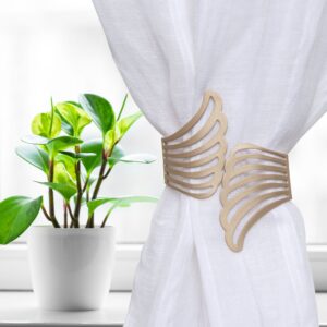 "Gold angel wings tieback on white curtain beside a potted plant on a windowsill"