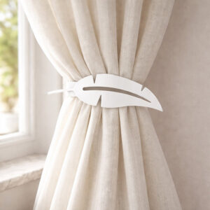 "White feather metal tieback holding cream curtain against wall"