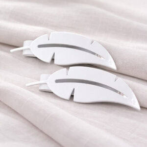 "Close-up of white shiny metal feather tiebacks on fabric"