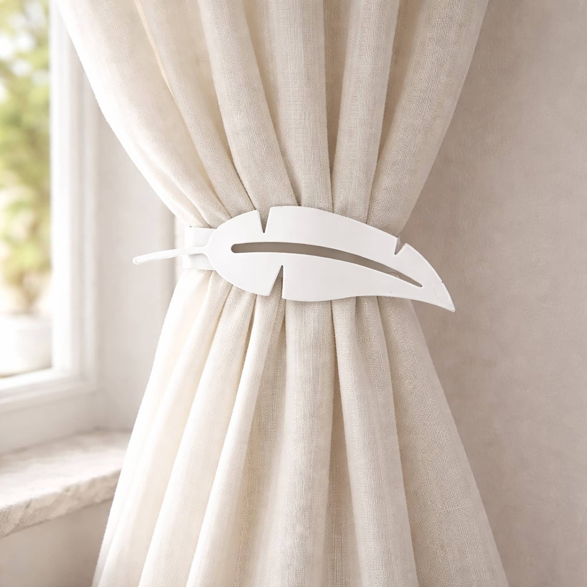 "White feather metal tieback holding cream curtain against wall"