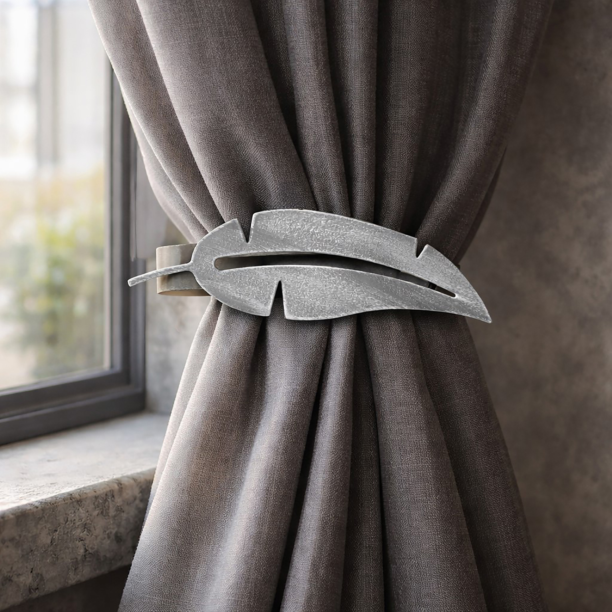 "Grey metal feather tieback holding grey curtain by window"