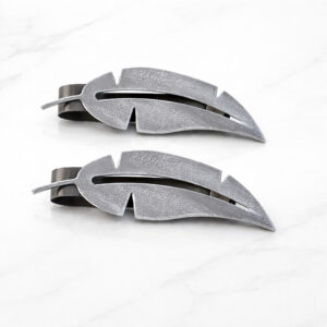 "Grey textured metal feather tiebacks on marble surface"